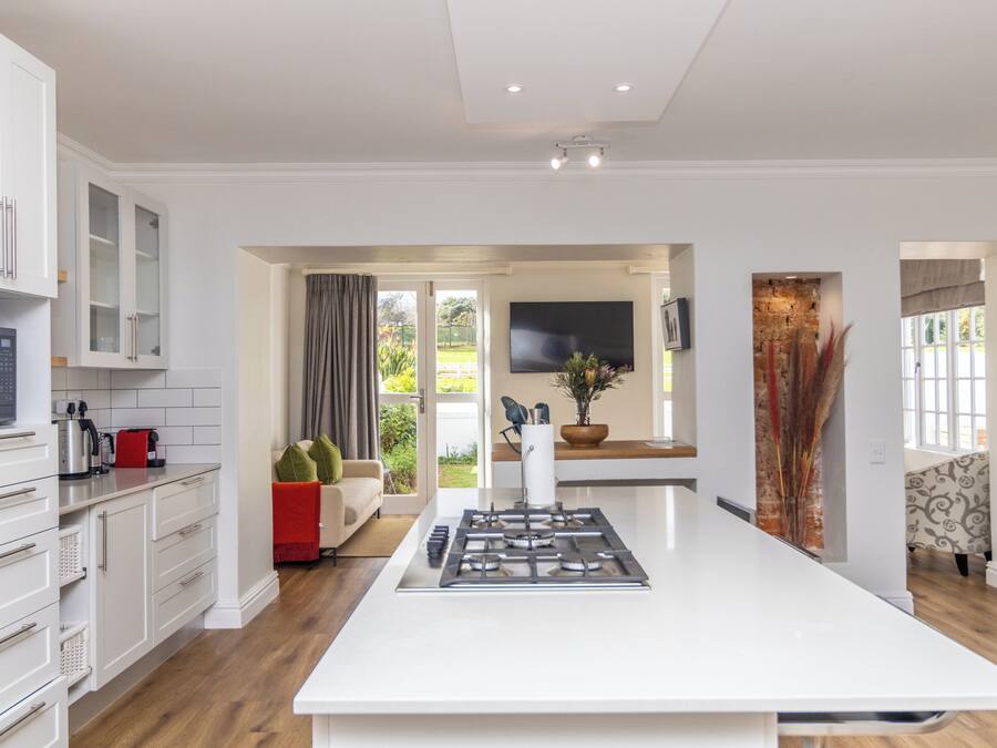 A modern kitchen with white cabinetry, a central island, and a flat-screen TV mounted on the wall.