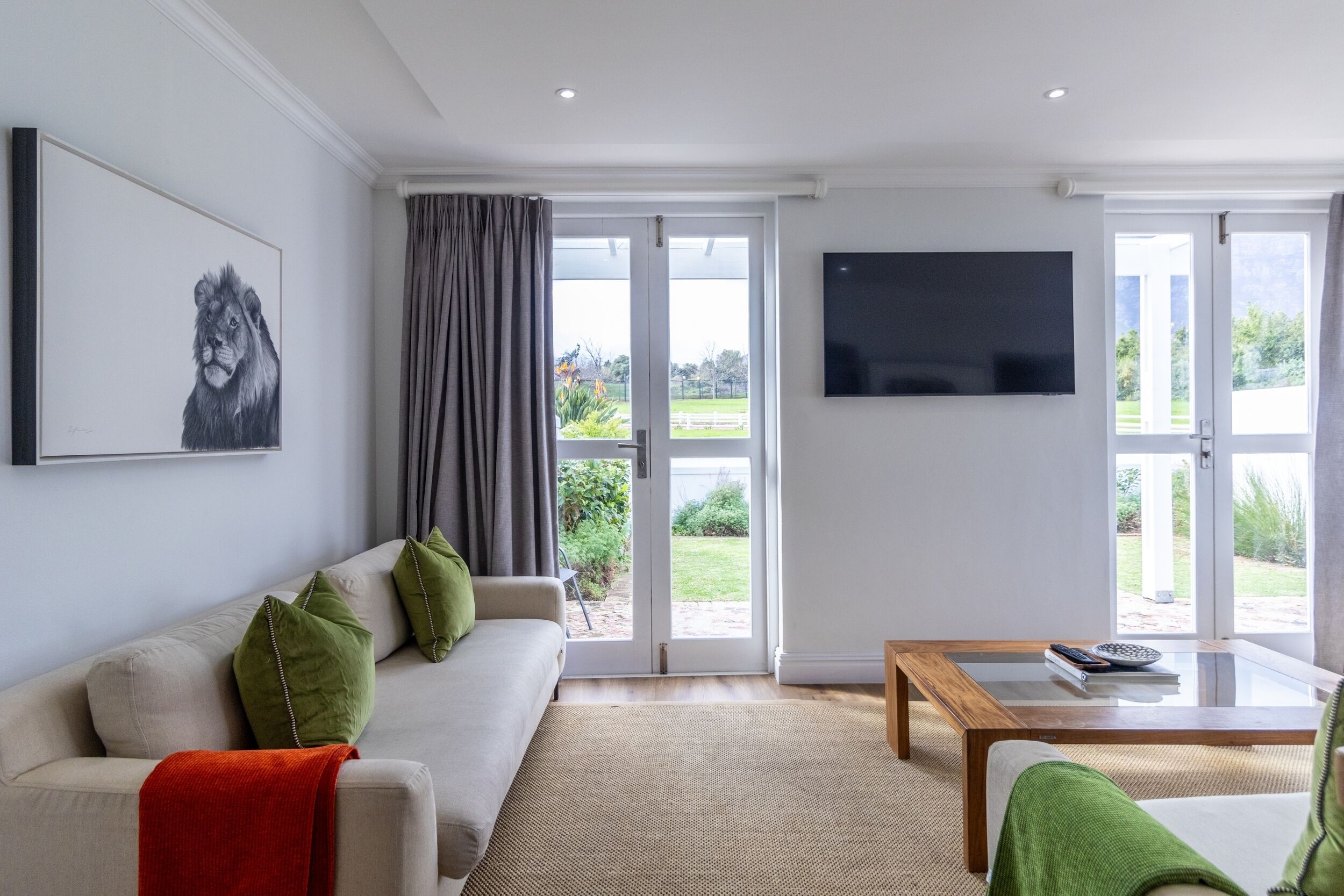 A modern living room with a sofa, a coffee table, and a TV mounted on the wall.
