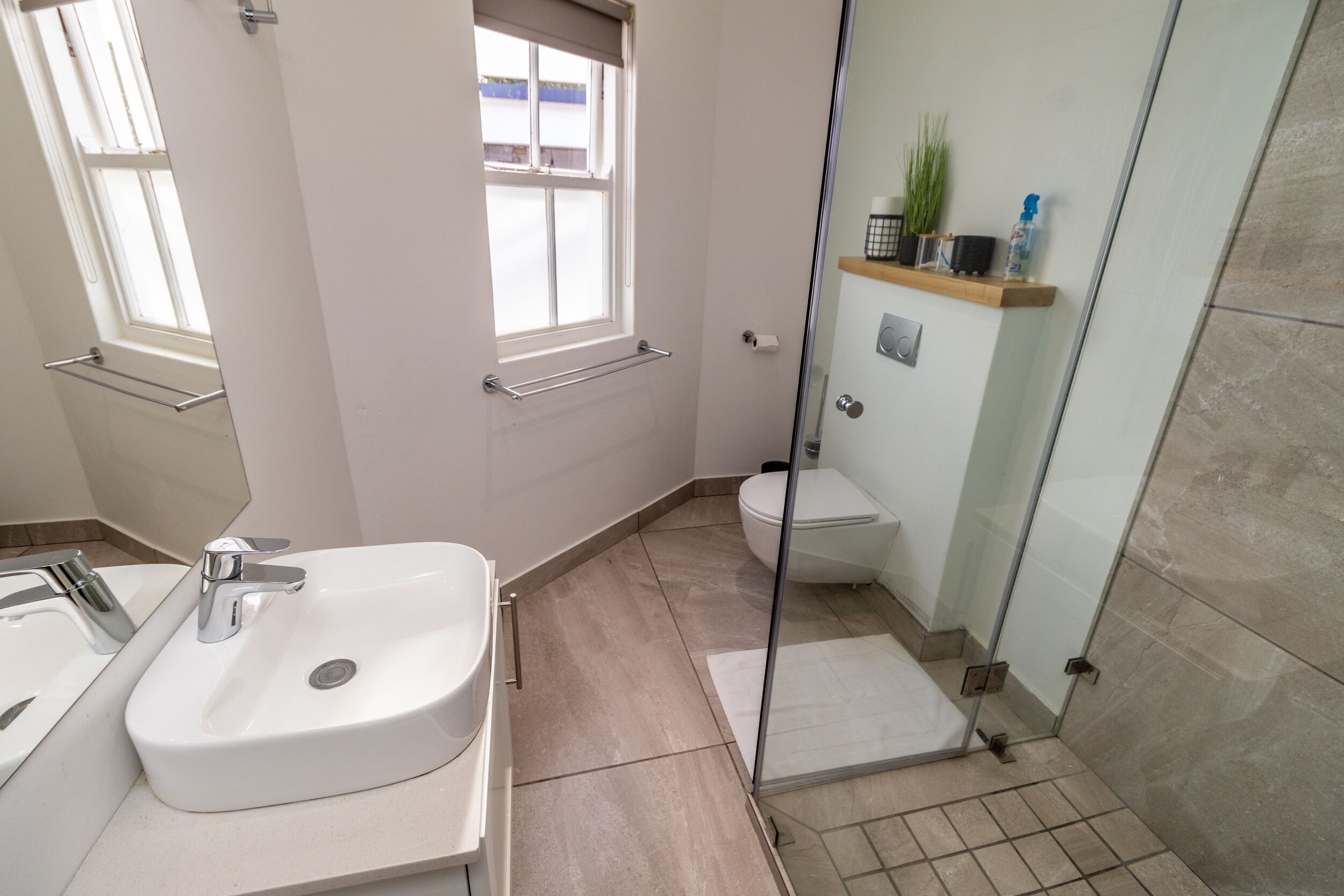 A modern bathroom with a white sink, a glass shower enclosure, and a toilet.
