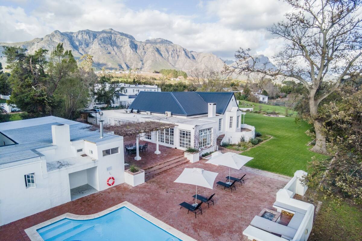 Une maison moderne dotée d’une piscine, d’un patio et offrant une vue sur les montagnes.