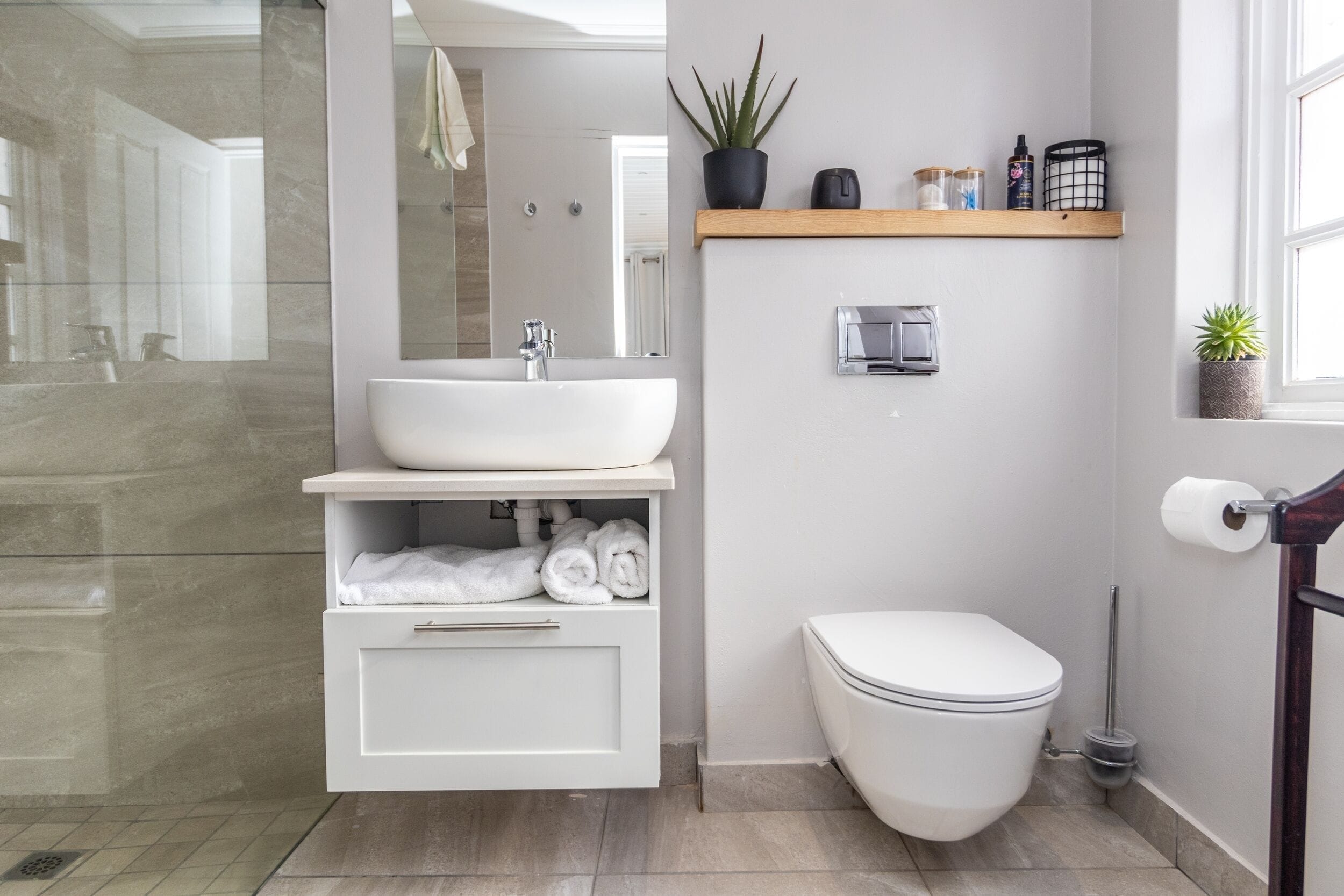 A modern bathroom with a white sink, a toilet, and a shower area.