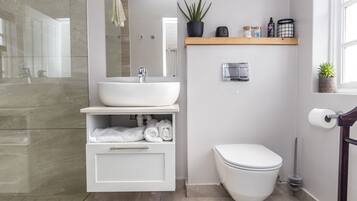 A modern bathroom with a white sink, a toilet, and a shower area.