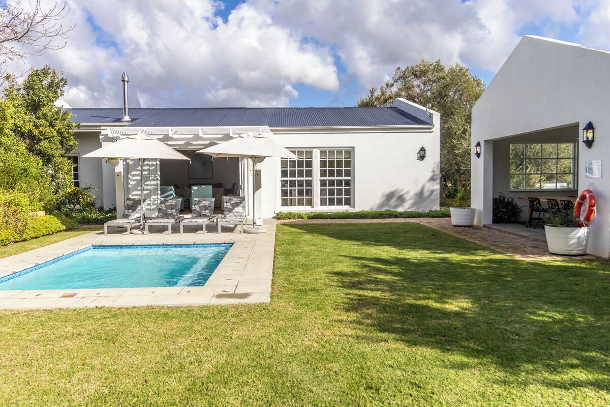 Une maison moderne dotée d’une piscine, d’un patio couvert et d’une pelouse bien entretenue.