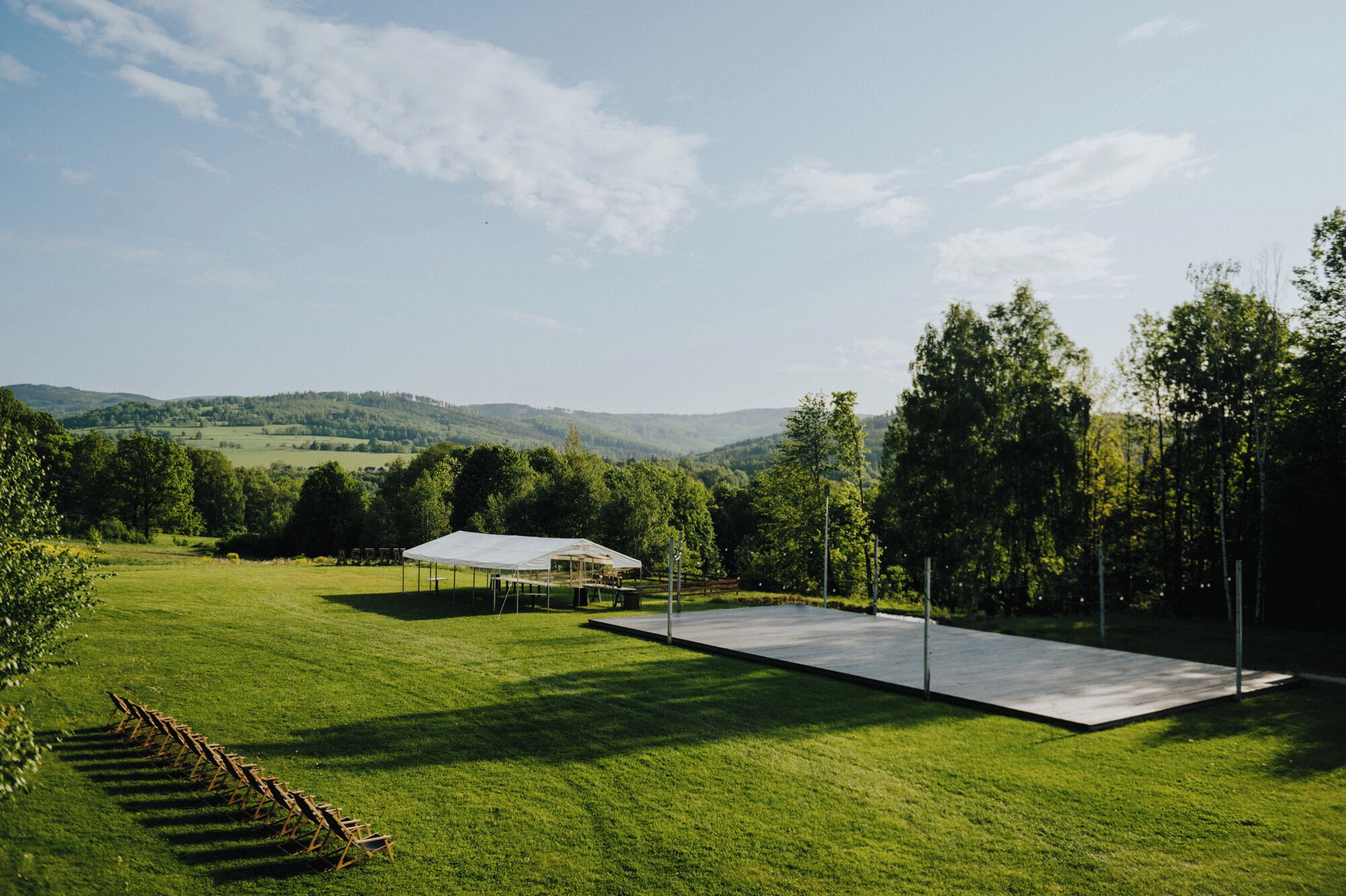 Un espace extérieur verdoyant avec une tente blanche et une plateforme en béton.