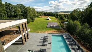A modern building with a rooftop pool, lounge chairs, and a tent in the background. - Aspen Prime Ski & Bike Resort (Podlesie)