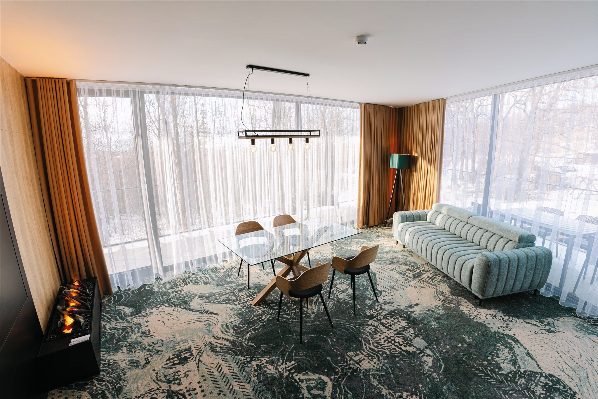 Una sala de estar moderna con una mesa de comedor de cristal, sillas de madera, un sofá y una chimenea.