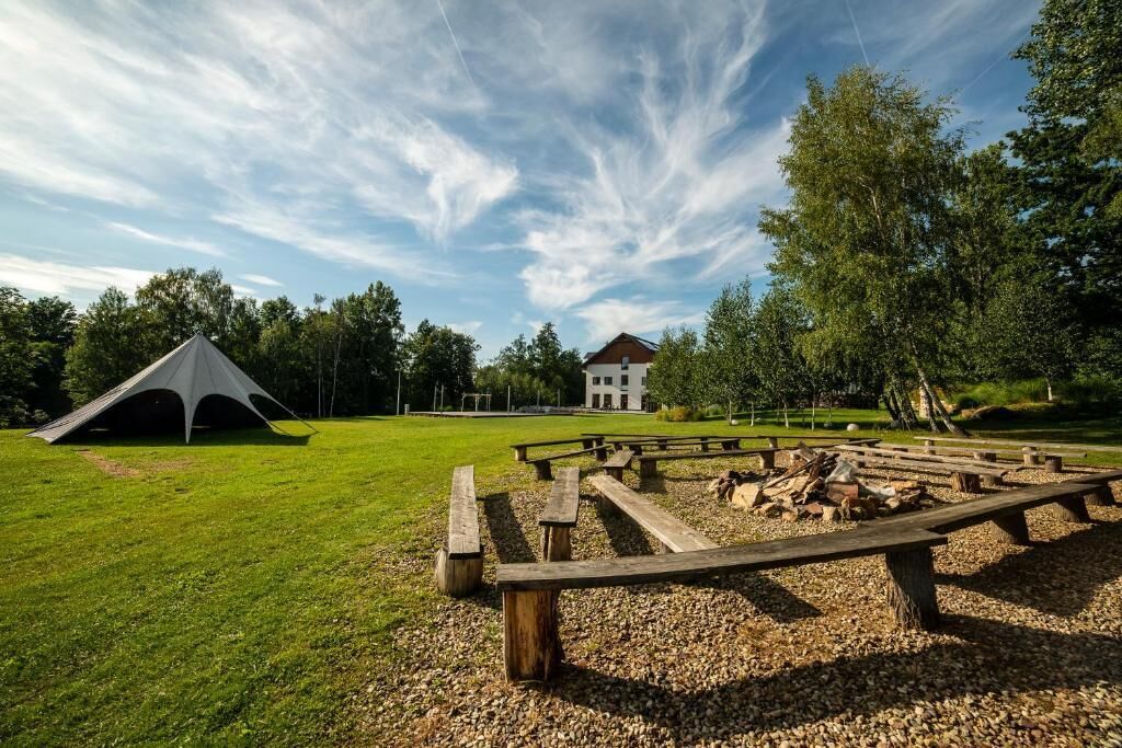 Ein Campingplatz mit Zelt, Picknicktischen und einem Gebäude im Hintergrund.