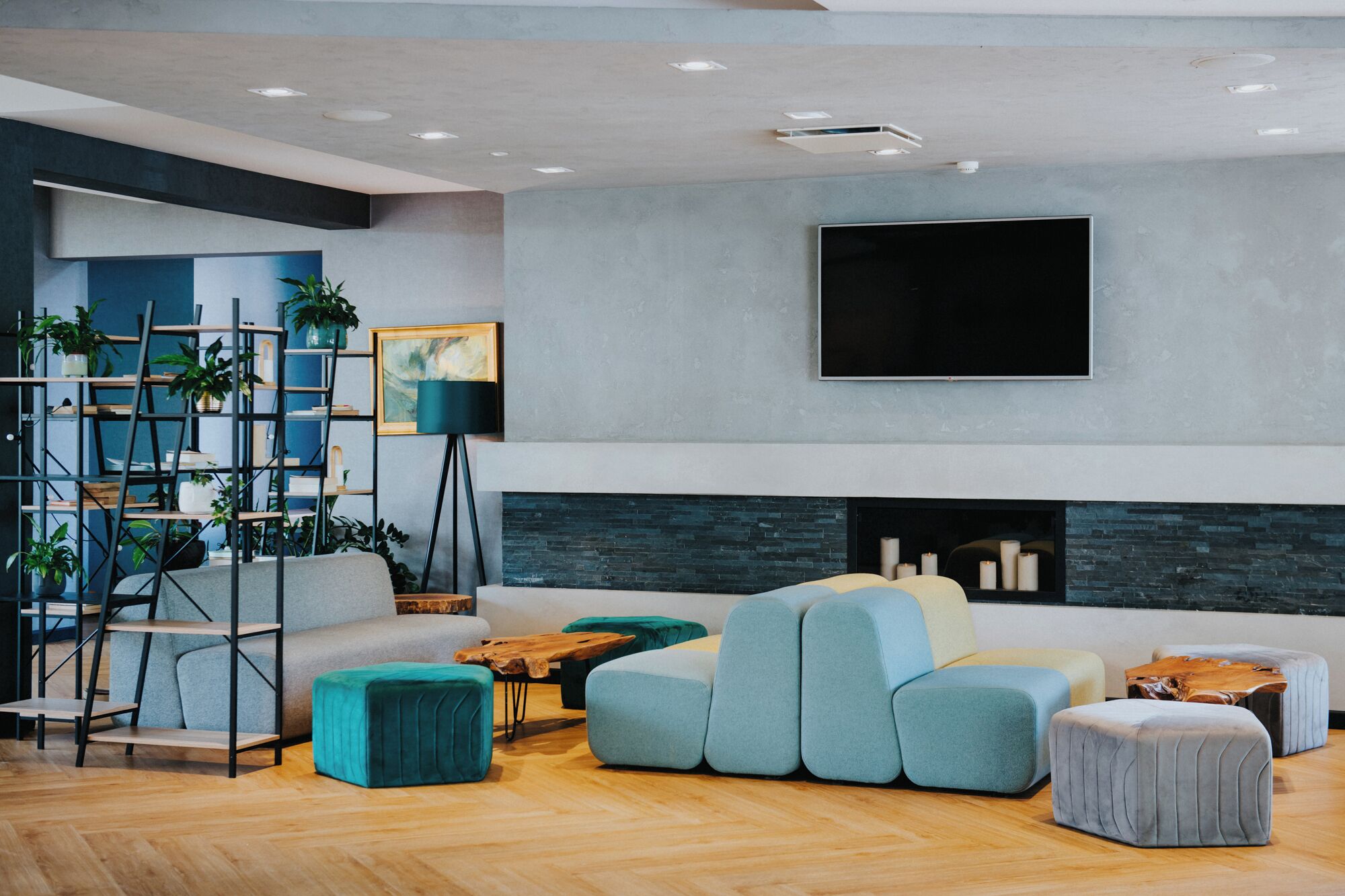 A modern living room with a fireplace, a large flat-screen TV, and a variety of seating options.