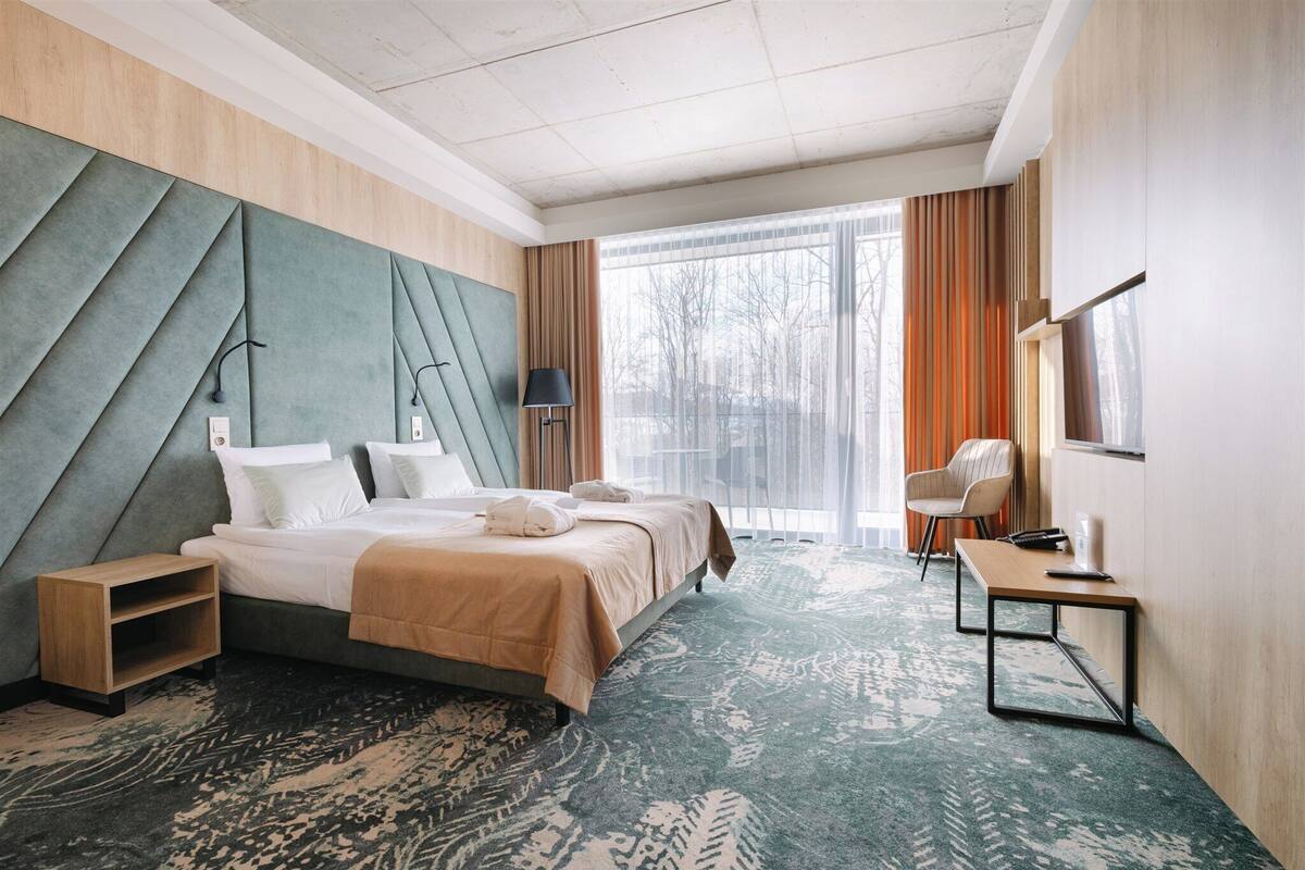 Une chambre d’hôtel avec un grand lit, un bureau, une chaise et une vue sur l’extérieur.
