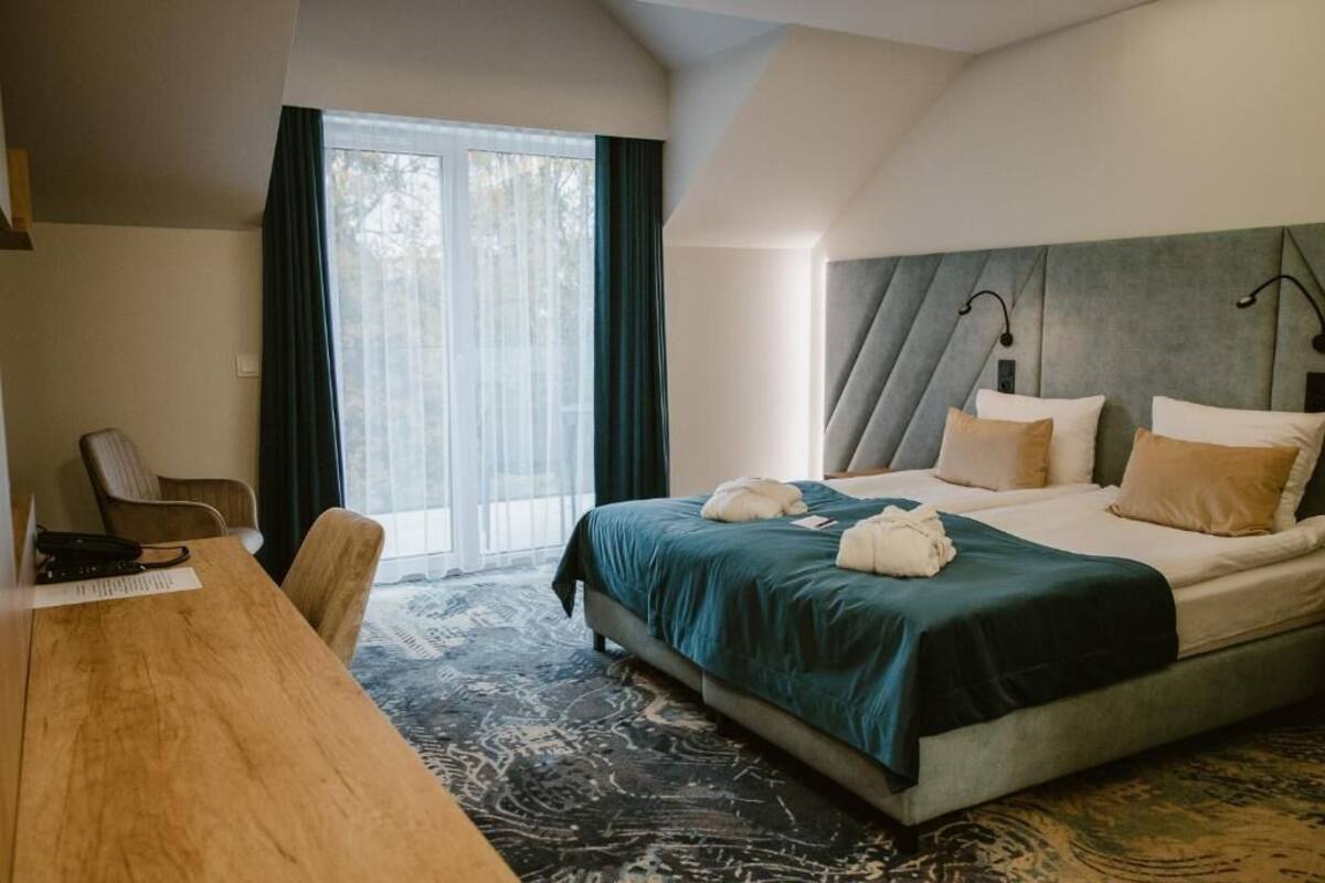 Une chambre d’hôtel avec un grand lit, un bureau en bois et une vue sur l’extérieur par la fenêtre.