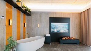 A modern bathroom with a freestanding bathtub, a wall-mounted toilet, and a built-in fireplace. - Aspen Prime Ski & Bike Resort (Podlesie)