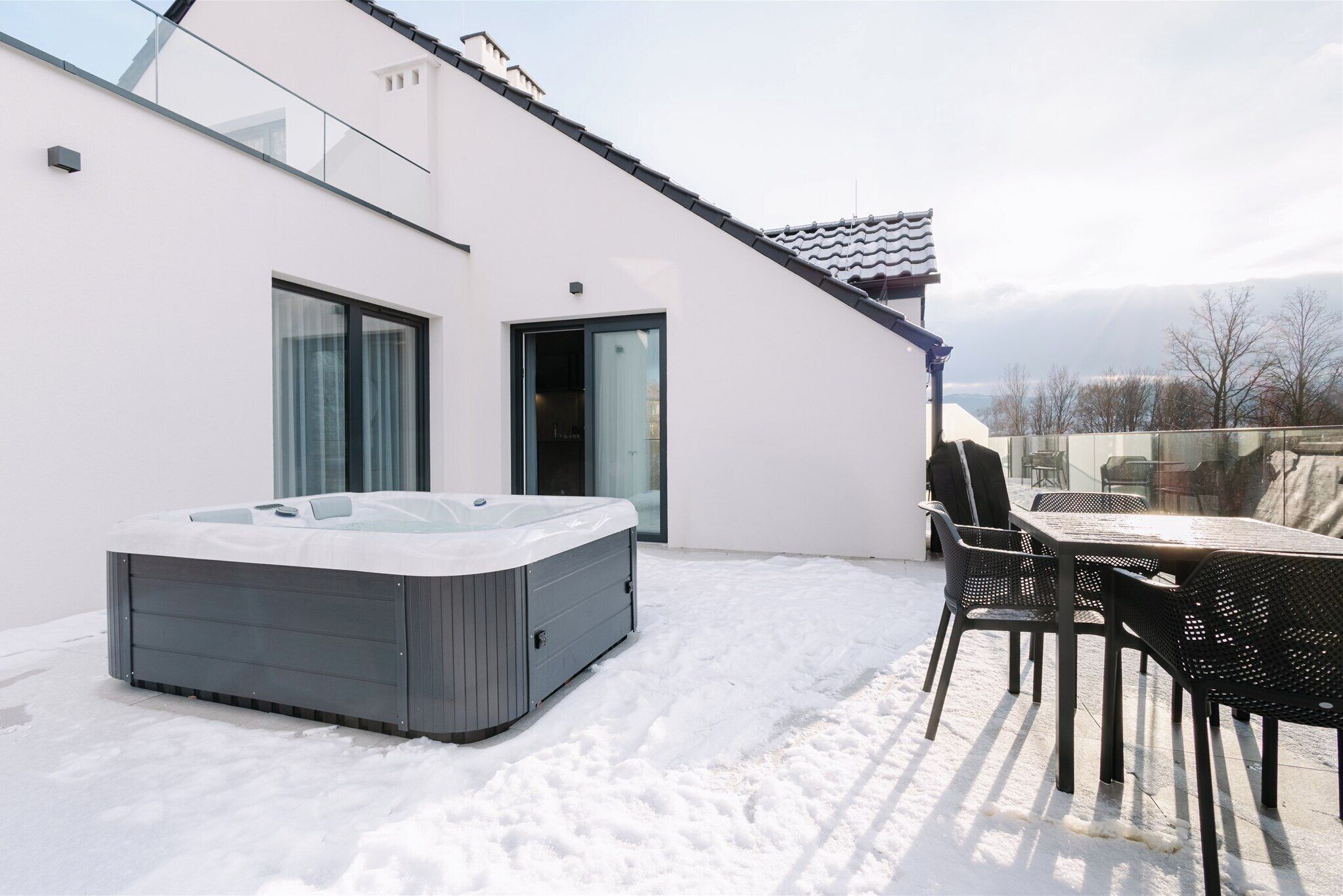 Un espacio exterior moderno con un jacuzzi, una mesa y sillas.