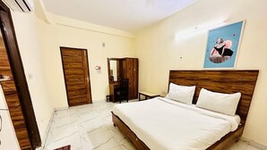 Ein Hotelzimmer mit einem hölzernen Bett, weißer Bettwäsche, einem Marmorboden, einem Holzschrank und einem gerahmten Bild an der Wand.