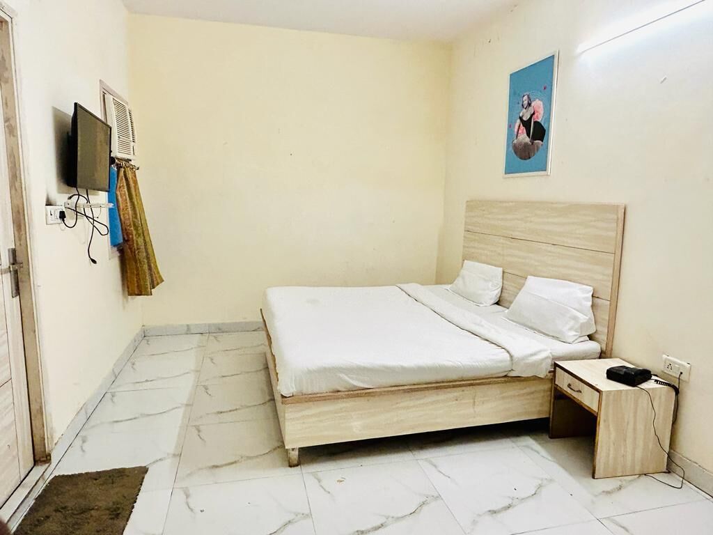 Un dormitorio con cama de madera, mesita de noche, televisor y aire acondicionado instalado en la pared.