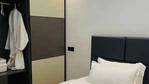Une chambre d’hôtel avec un lit, une armoire et un peignoir accroché à la porte.