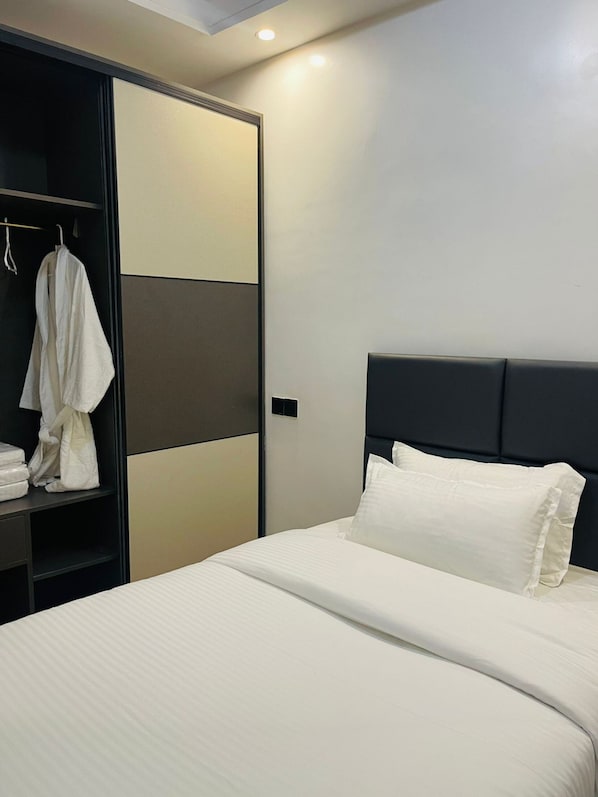Una habitación de hotel con una cama, un armario y una bata colgada en la puerta.