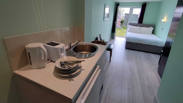 Een moderne hotelkamer met een kitchenette, een bed en uitzicht op de omgeving.