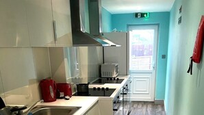 Een moderne keuken met een wasmachine, magnetron en kookplaat.