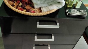 Een zwarte dressoir met een witte handdoek en een mand vol gedroogde bloemen.