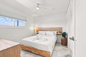 Ein modernes Schlafzimmer mit Bett, Nachttisch, Lampe und Blick zum Himmel.