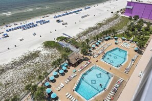 Un complexe hôtelier de bord de mer doté d’une piscine, de chaises longues et de parasols.