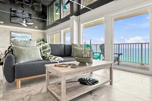 A modern living room with a grey sofa, a wooden coffee table, and a view of the ocean. - The Summit 1512 - Your Ultimate Vacation Retreat! (Panama City)