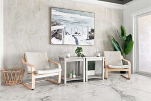 Ein Zimmer mit zwei Stühlen, einem Tisch und einem großen Gemälde einer verschneiten Landschaft.