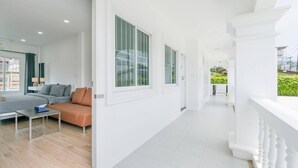 A modern, bright room with a sofa, a small table, and large windows. - Charming Studio Suite - Private Washer  (Chalong)