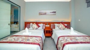 Quarto de hotel com duas camas, um quadro na parede e vista para o mar.
