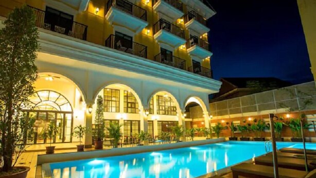 Um hotel com piscina, várias varandas e áreas de estar ao ar livre.