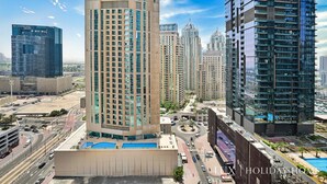 A high-rise building with a modern design, featuring a prominent vertical structure and a rooftop pool area.