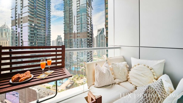 A balcony with a wooden bench, a sofa, and a table with food and drinks.