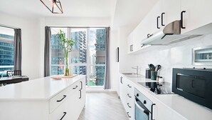 A modern kitchen with white cabinetry, a large window with a city view, and a central island with a plant.