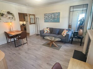 A modern living room with a sofa, a dining table with chairs, a coffee table, and a fireplace.