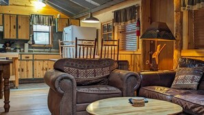 Een landelijk houten interieur met een eettafel, leren banken en een keukenhoek.