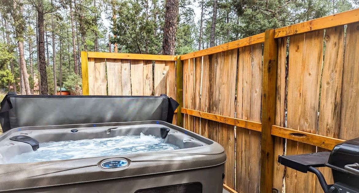 A hot tub with a wooden fence in the background.