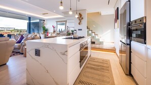 A modern kitchen with a marble island, built-in oven, and stainless steel appliances. - 1 Savili - Zululami (Ballito)
