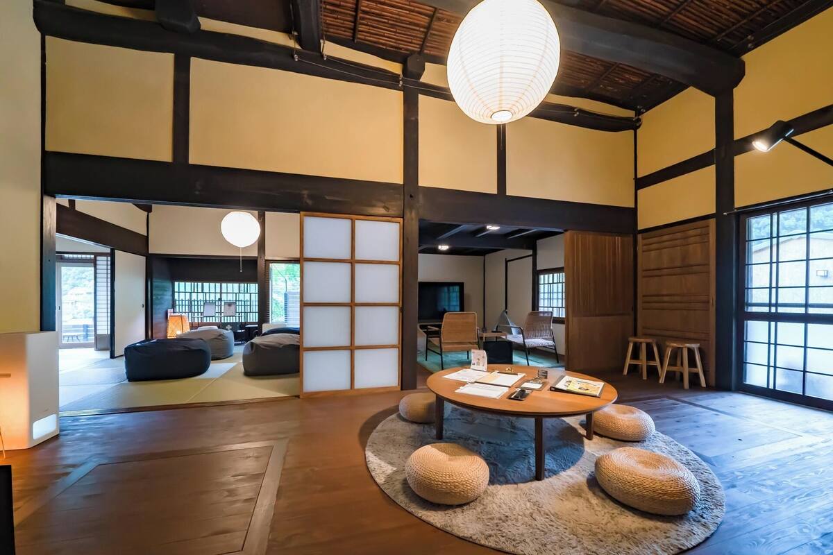 A traditional Japanese room with tatami flooring, a low table with papers, and a hanging paper lantern.