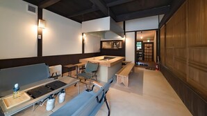 A compact kitchen with a central island, a dining area with a bench, and a small seating area with a table and chairs. - Tagomori no Akari (Ukiha)