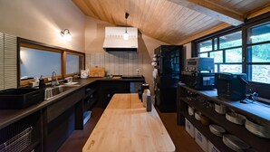 A modern kitchen with wooden beams, a large window, and a built-in oven. - Tagomori no Akari (Ukiha)
