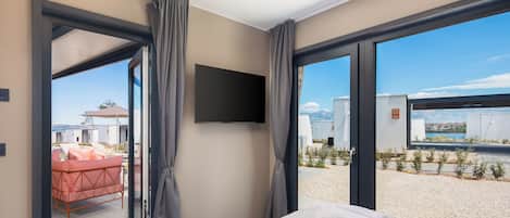 Une chambre d’hôtel moderne dotée d’un grand lit, d’une télévision à écran plat et offrant une vue sur une piscine et un espace extérieur.