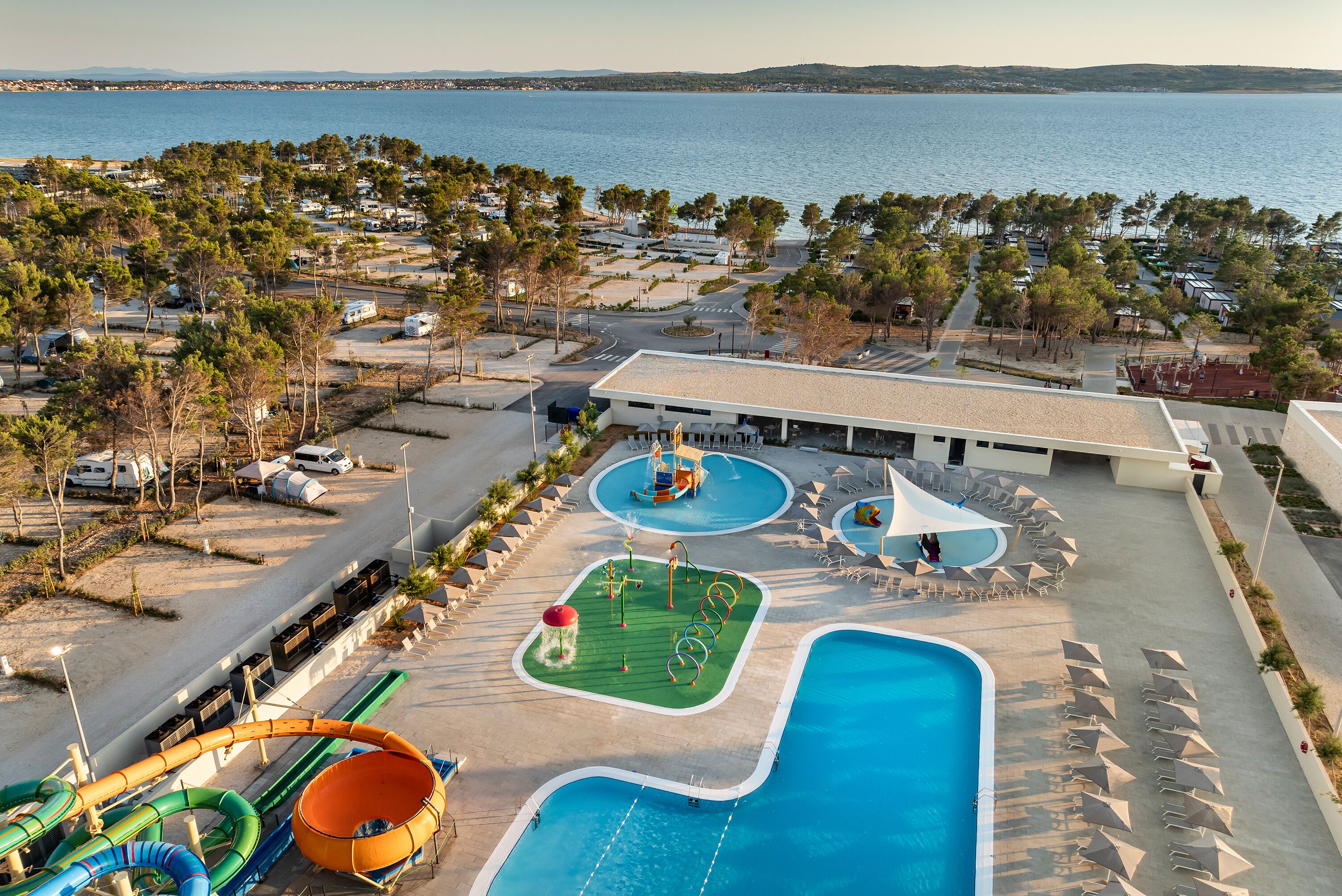 A resort with a pool area, water slides, and a view of the sea.