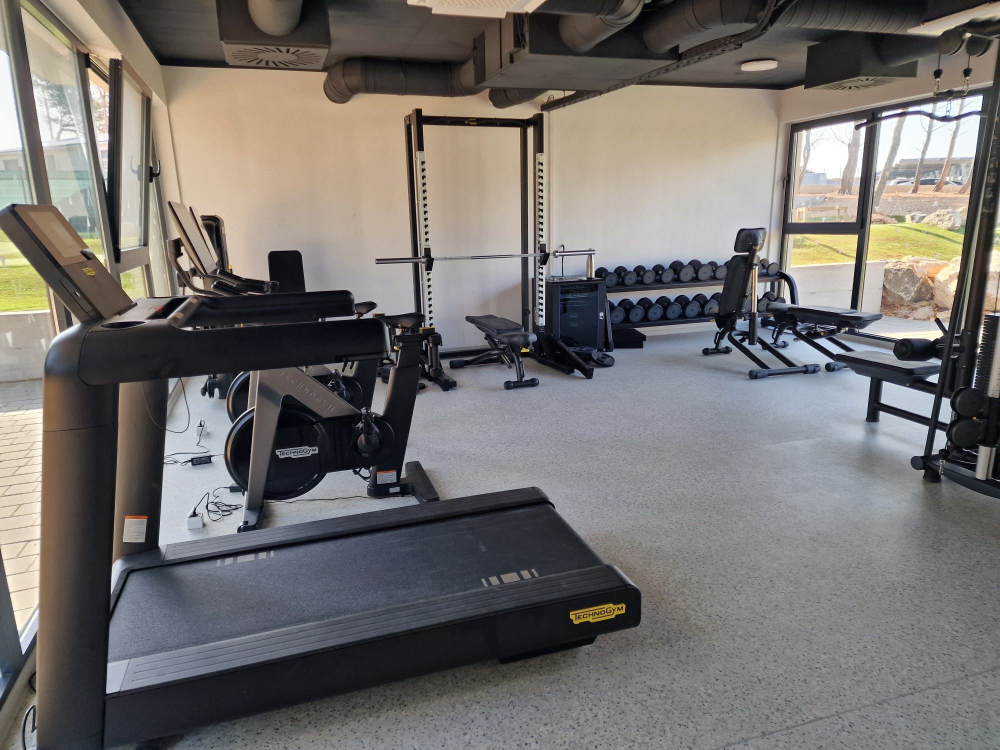 Ett gym med konditionsmaskiner, styrketräningsstationer och hantlar.