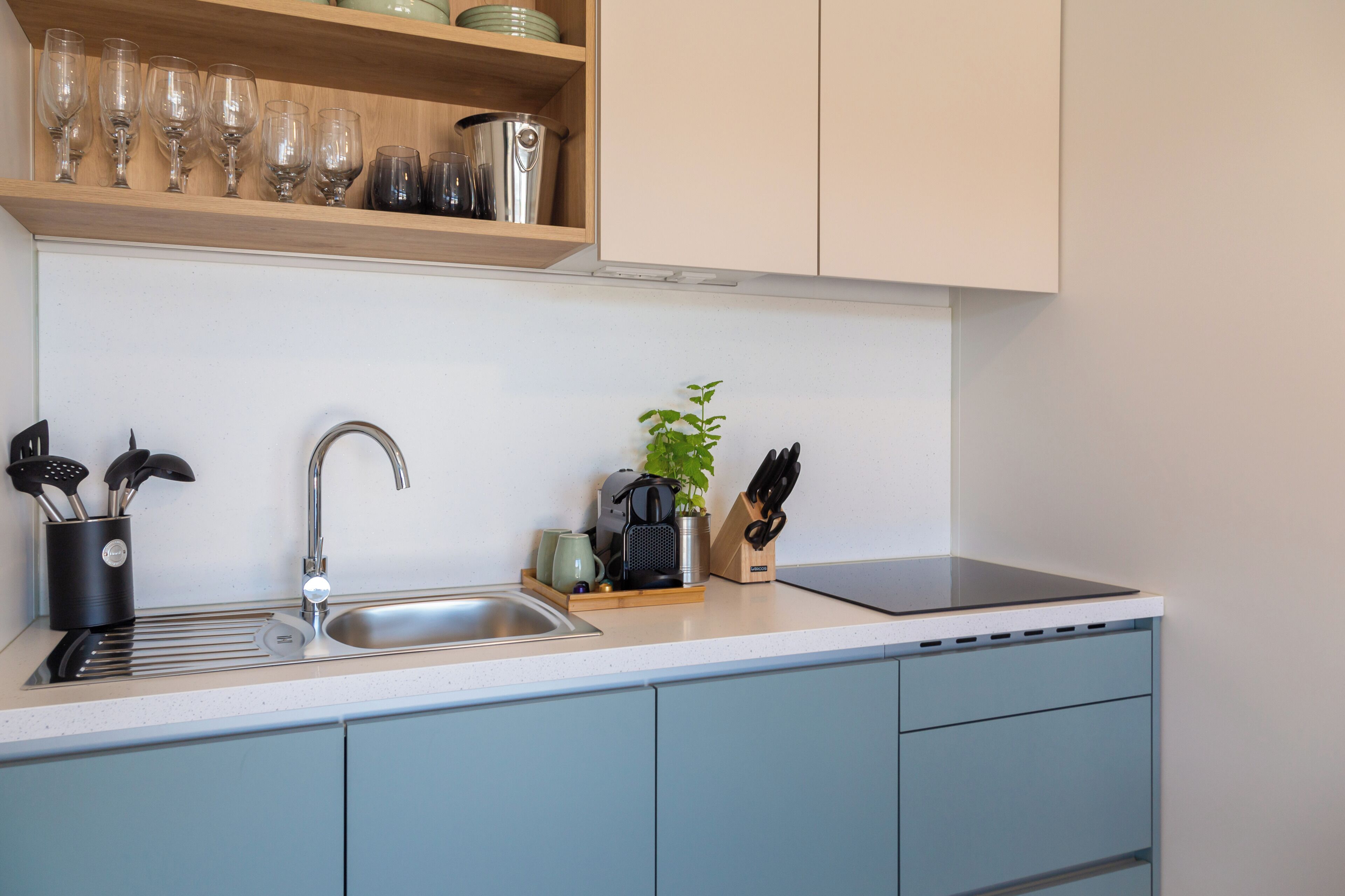 A kitchen with a stainless steel sink, a coffee machine, and a knife block.