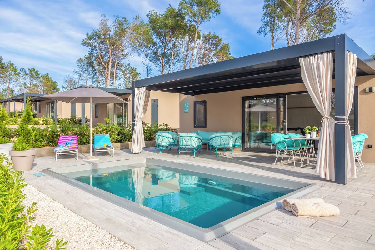 Ein moderner Poolbereich im Freien mit überdachter Lounge, Liegestühlen und einem Billardtisch.