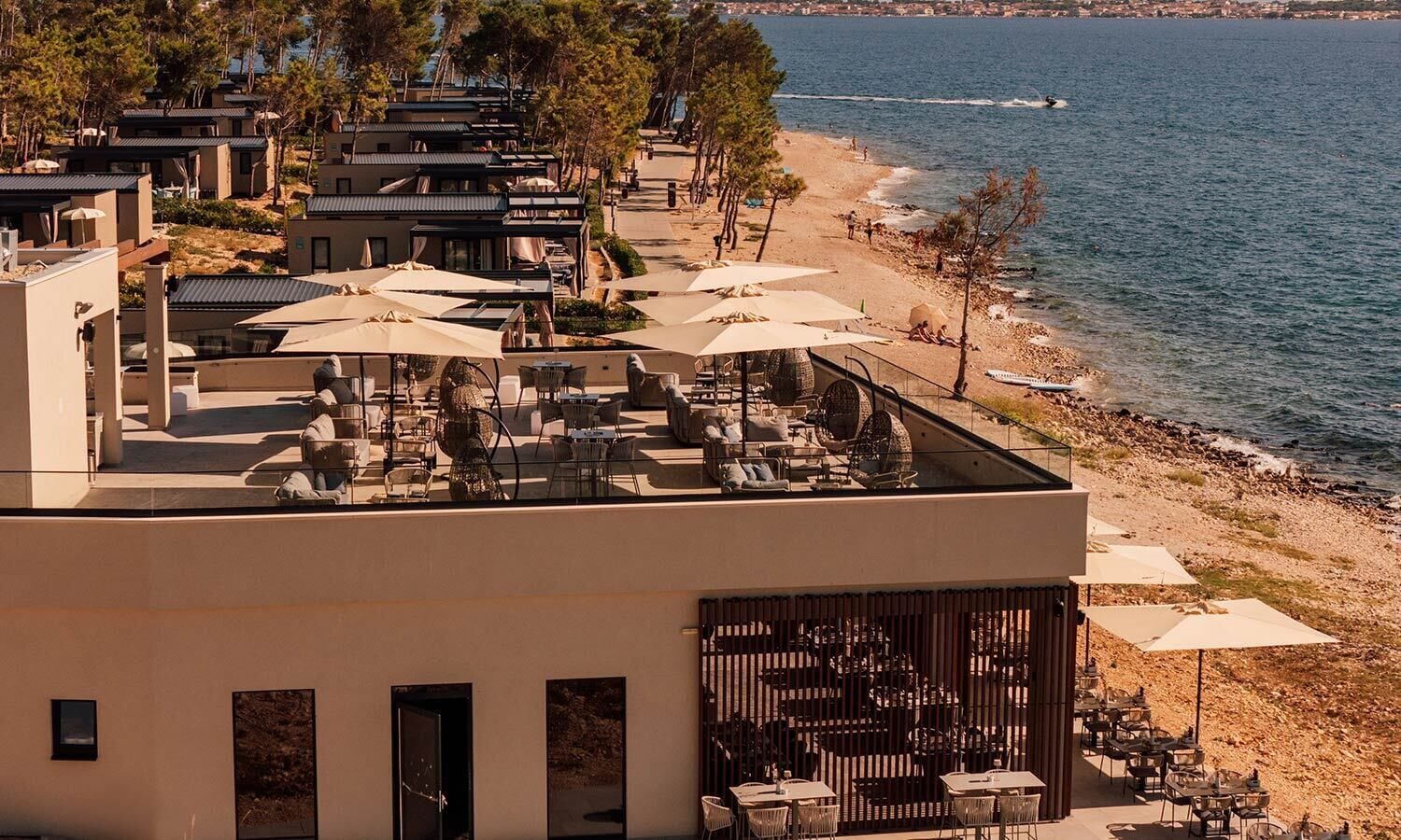 Une terrasse sur le toit, avec des sièges en plein air, offrant une vue sur une plage et la mer.