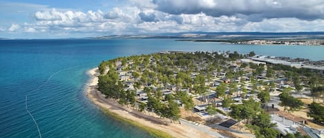 Ilmakuva rannikkoalueesta, jossa on ranta, useita rakennuksia ja selkeä näkymä merelle.
