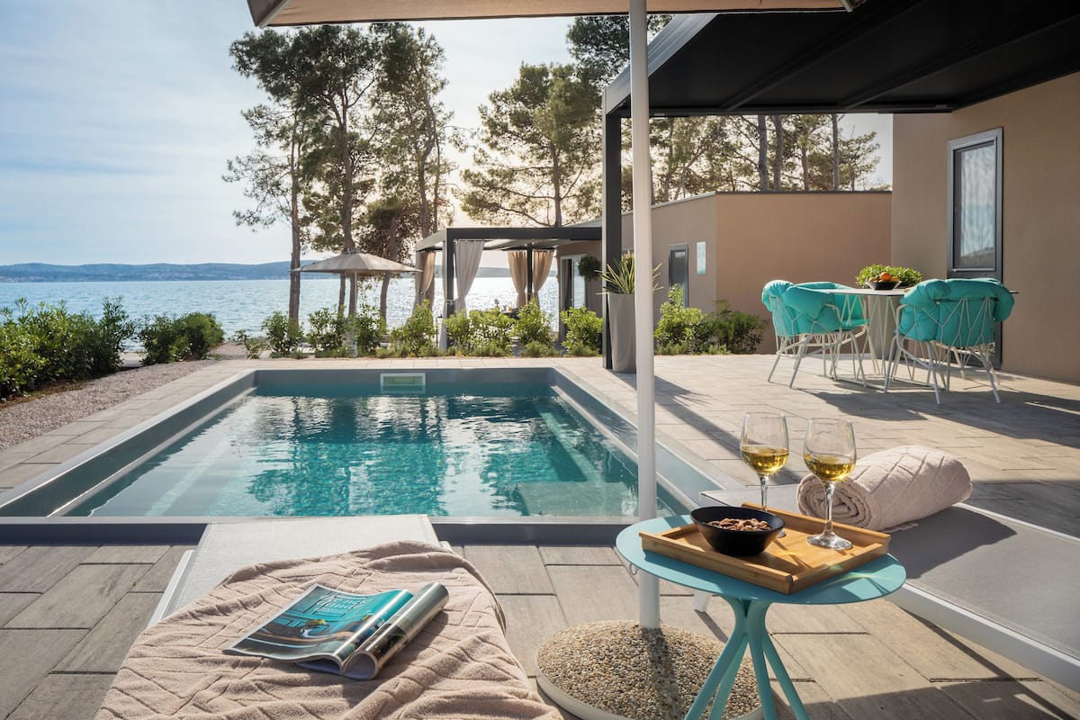 Ein Poolbereich mit Meerblick, ein Tisch mit Getränken und einer Zeitschrift.