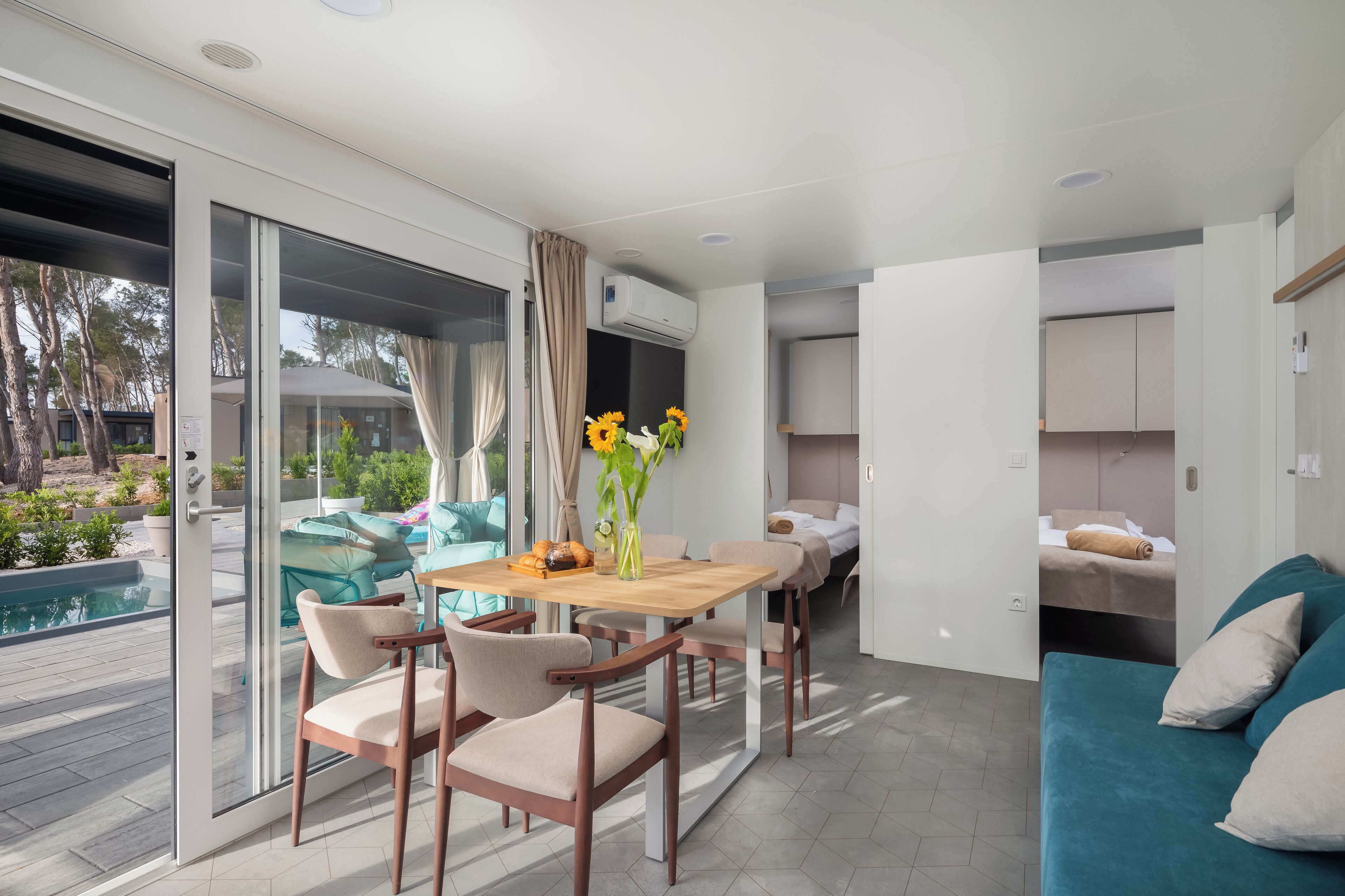 Un salon moderne comprenant un coin repas, un canapé et donnant sur une piscine.