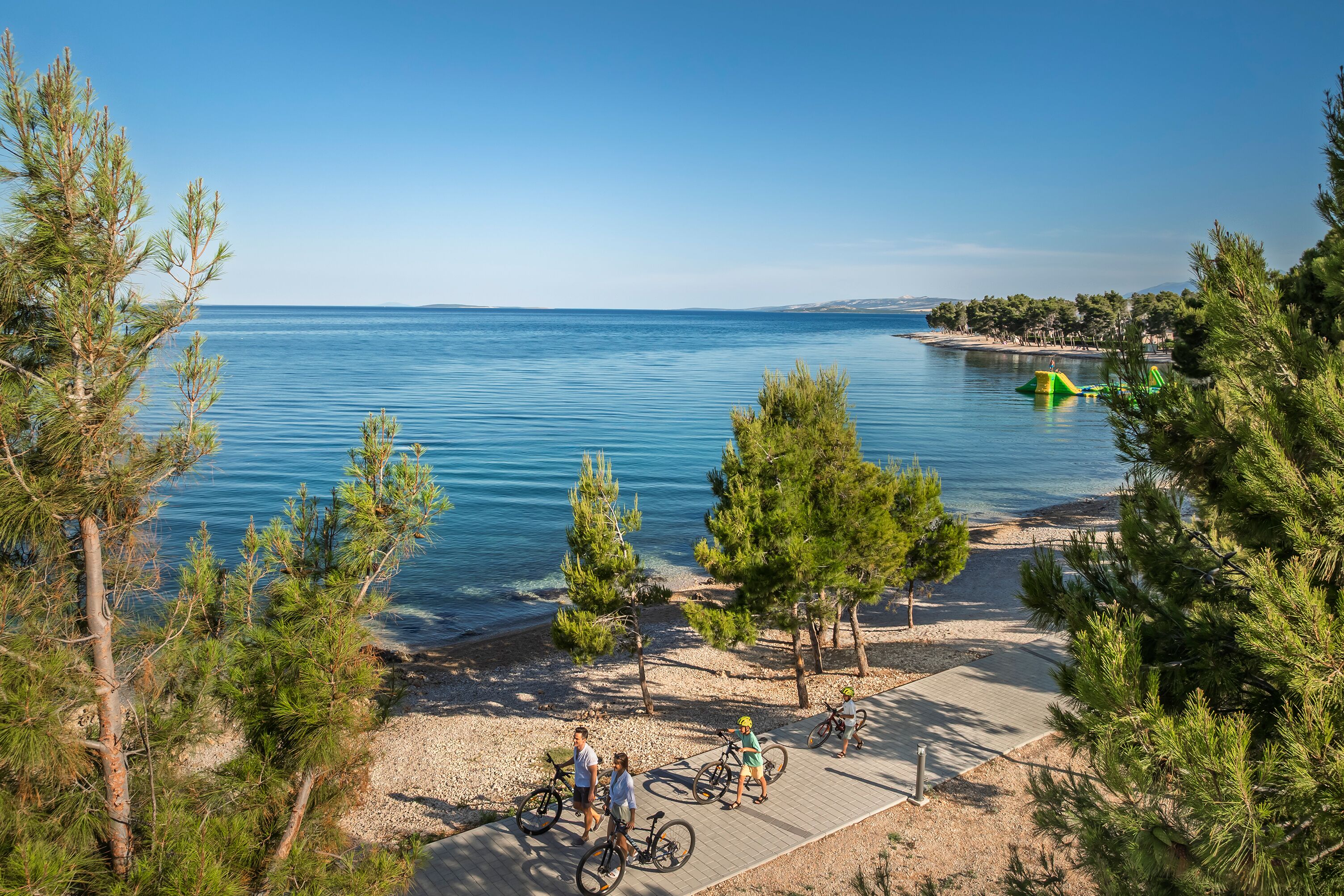 A coastal area with a paved walkway, bicycles, and a clear view of the sea.